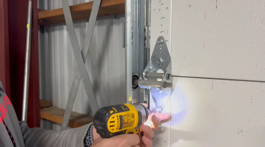 Technician removing an old garage door roller bracket during a repair in Irving, TX